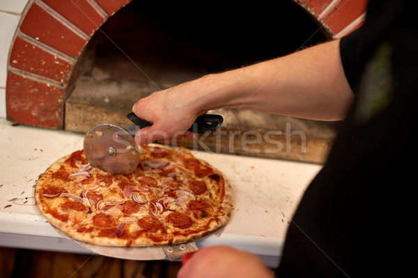 cook hands cutting pizza to pieces at pizzeria Stock photo © dolgachov