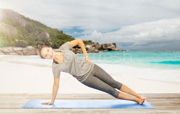 woman doing yoga in side plank pose on beach Stock photo © dolgachov