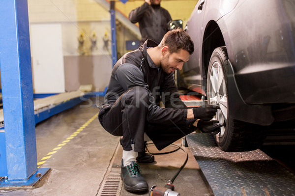 Stock photo: auto mechanic with screwdriver changing car tire