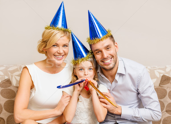 Stock photo: smiling family in blue hats blowing favor horns