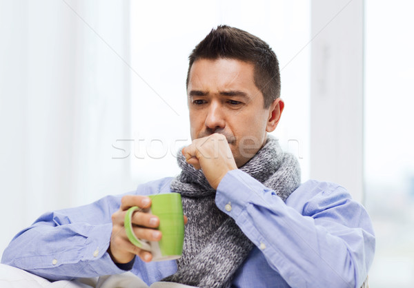 ill man with flu drinking tea and coughing at home Stock photo © dolgachov