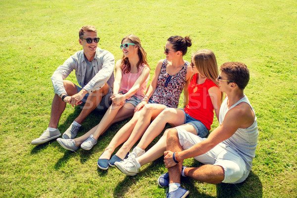 group of smiling friends outdoors sitting in park Stock photo © dolgachov