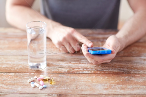 close up of hands with smartphone, pills and water Stock photo © dolgachov