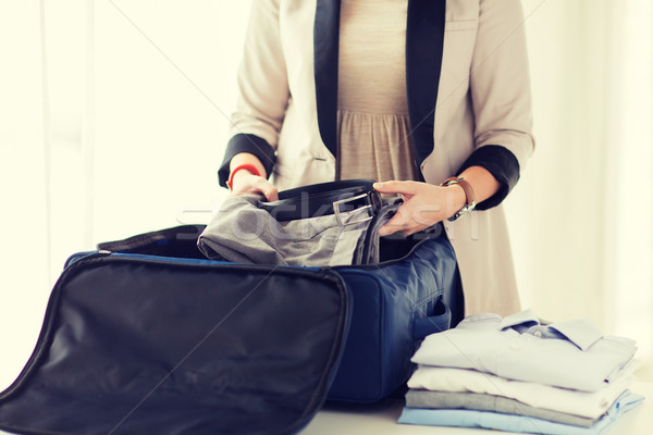 woman packing formal male clothes into travel bag Stock photo © dolgachov