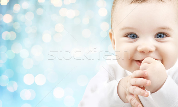 Stock photo: happy baby face over blue holidays lights