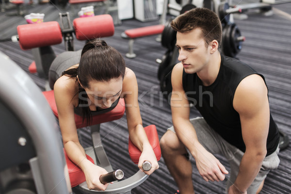 young woman with trainer exercising on gym machine Stock photo © dolgachov