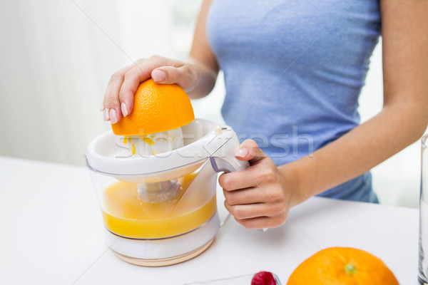 close up of woman squeezing orange juice at home Stock photo © dolgachov