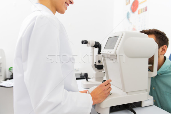 optician with autorefractor and patient at clinic Stock photo © dolgachov