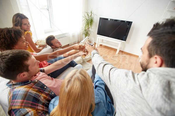 friends clinking beer and watching tv at home Stock photo © dolgachov