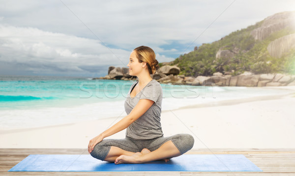 woman doing yoga in twist pose on beach Stock photo © dolgachov