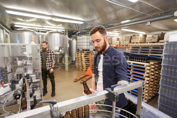 men with bottles on conveyor at craft beer brewery Stock photo © dolgachov