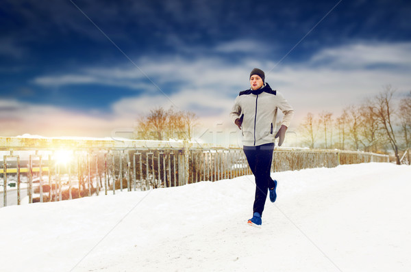 man running along snow covered winter bridge road Stock photo © dolgachov