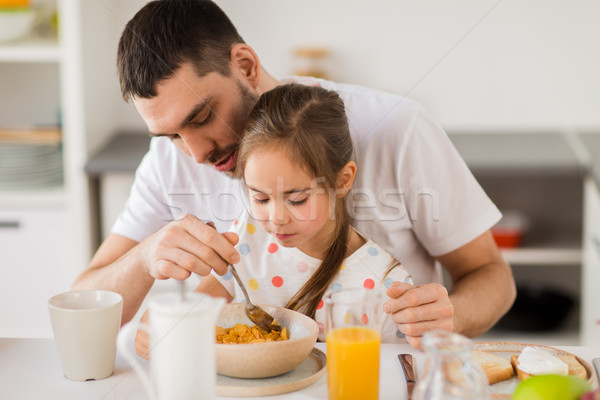 Stock photo: happy family eating flakes for breakfast at home
