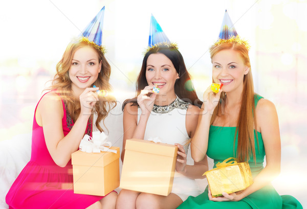 three women wearing hats with gifts blowing horns Stock photo © dolgachov