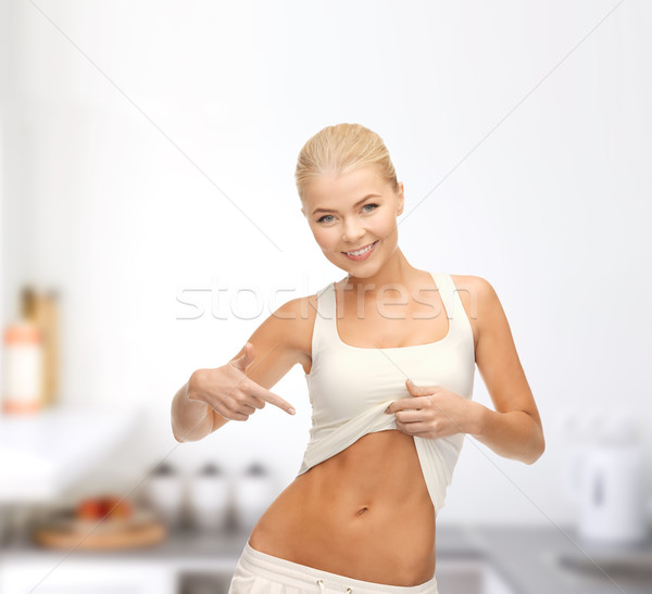 beautiful sporty woman pointing at her abs Stock photo © dolgachov