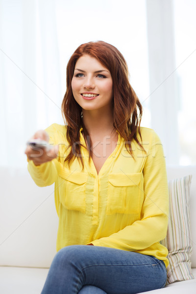 smiling young girl with tv remote control at home Stock photo © dolgachov