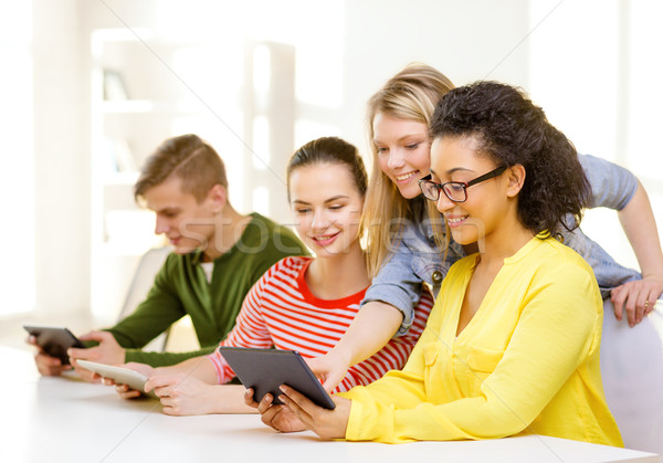 Stock photo: smiling students looking at tablet pc at school