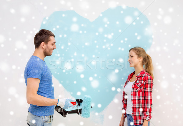 smiling couple painting big heart on wall Stock photo © dolgachov