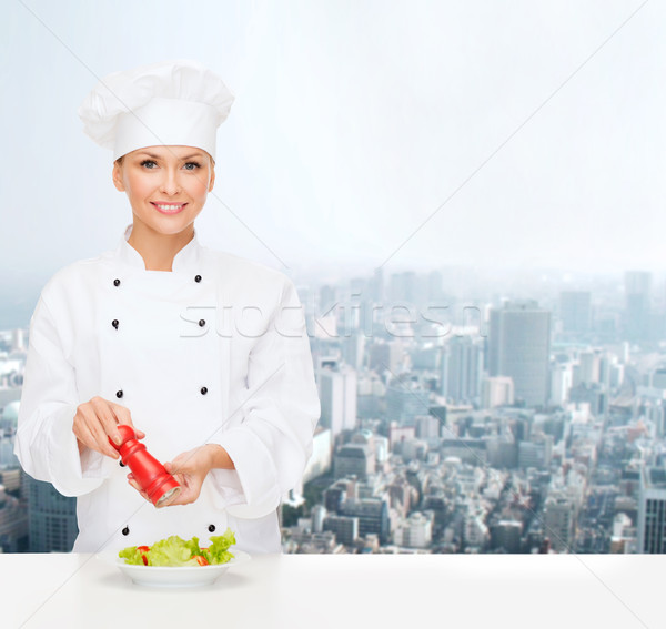 smiling female chef spicing vegetable salad Stock photo © dolgachov