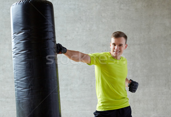 Stock photo: young man in gloves boxing with punching bag