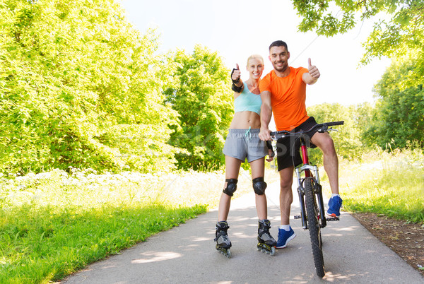 couple on rollerblades and bike showing thumbs up Stock photo © dolgachov