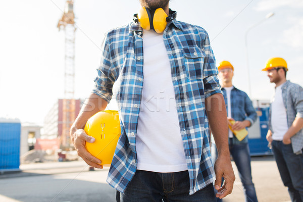 close up of builder holding hardhat at building Stock photo © dolgachov