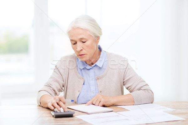 senior woman with papers and calculator at home Stock photo © dolgachov