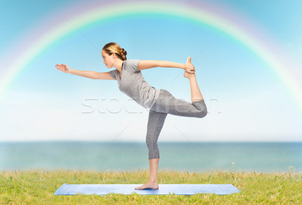 woman making yoga in lord of the dance pose on mat Stock photo © dolgachov