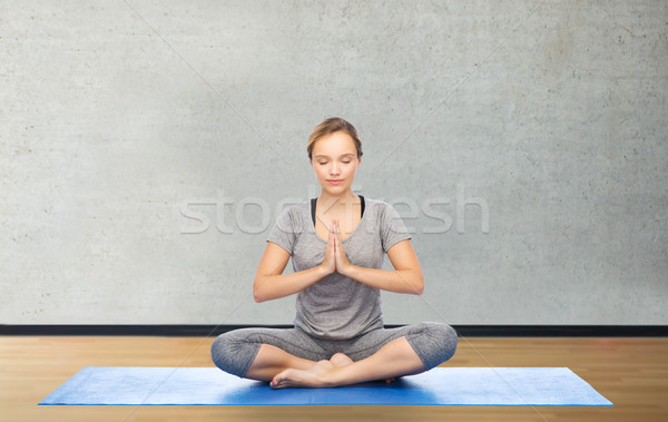 woman making yoga meditation in lotus pose on mat Stock photo © dolgachov