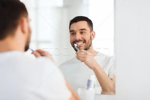 Homme brosse à dents nettoyage dents salle de bain [[stock_photo]] © dolgachov