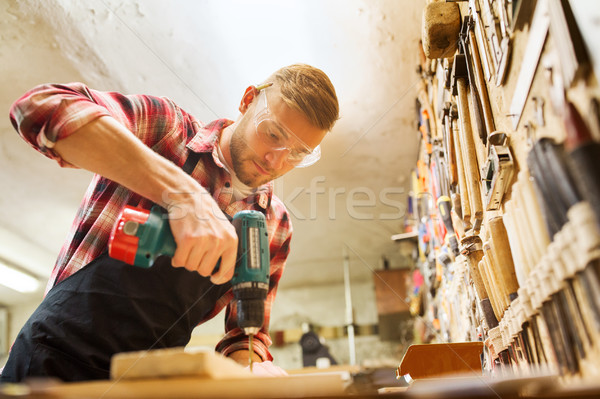 carpenter with drill drilling plank at workshop Stock photo © dolgachov