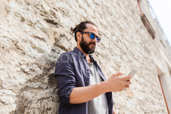 man texting message on smartphone at stone wall Stock photo © dolgachov