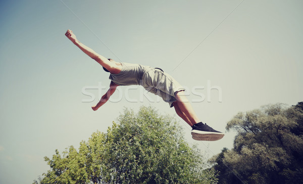 sporty young man jumping in summer park Stock photo © dolgachov