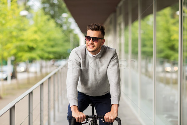 young man in shades riding bicycle on city street Stock photo © dolgachov