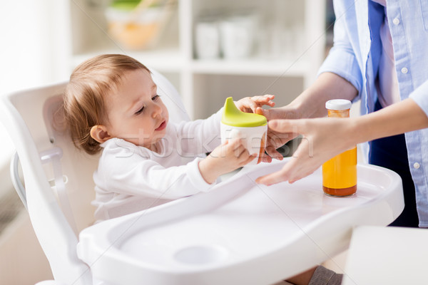 mother giving spout cup with juice to baby at home Stock photo © dolgachov