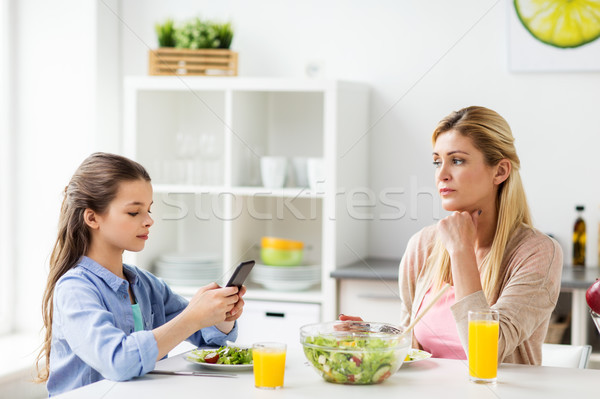 sad woman looking at her daughter with smartphone Stock photo © dolgachov