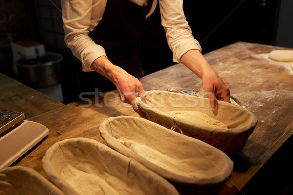 baker with dough rising in baskets at bakery Stock photo © dolgachov