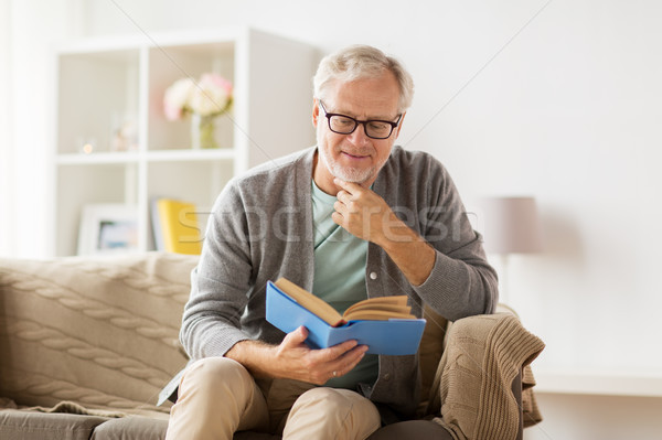 senior man on sofa reading book at home Stock photo © dolgachov