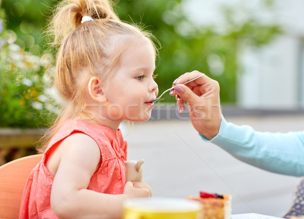 mother hand with spoon feeding daughter at cafe Stock photo © dolgachov