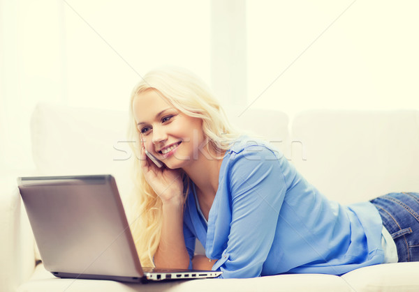 smiling woman with smartphone and laptop at home Stock photo © dolgachov