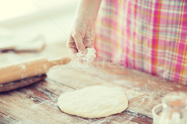 closeup of female hand sprinkling dough with flour Stock photo © dolgachov