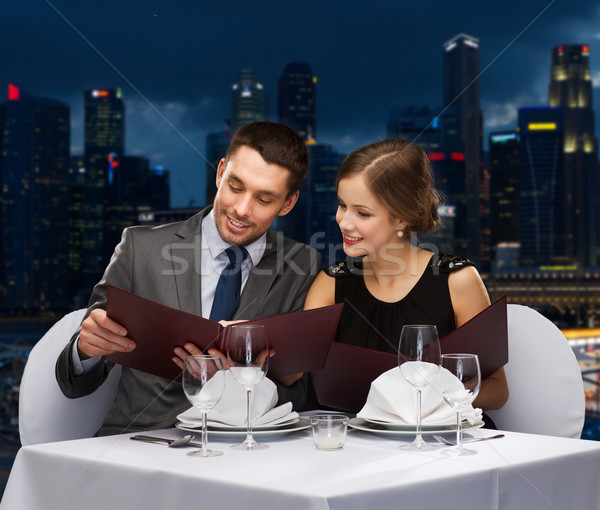 smiling couple with menus at restaurant Stock photo © dolgachov