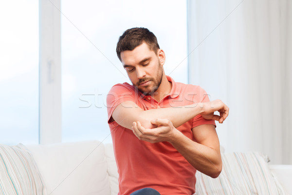 unhappy man suffering from pain in hand at home Stock photo © dolgachov