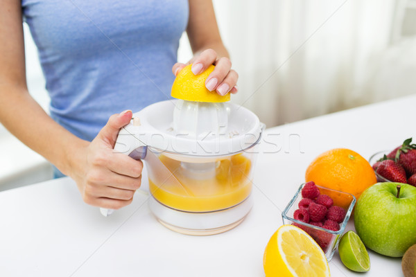 close up of woman squeezing fruit juice at home Stock photo © dolgachov