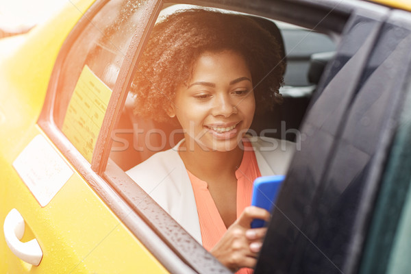 happy african woman texing on smartphone in taxi Stock photo © dolgachov