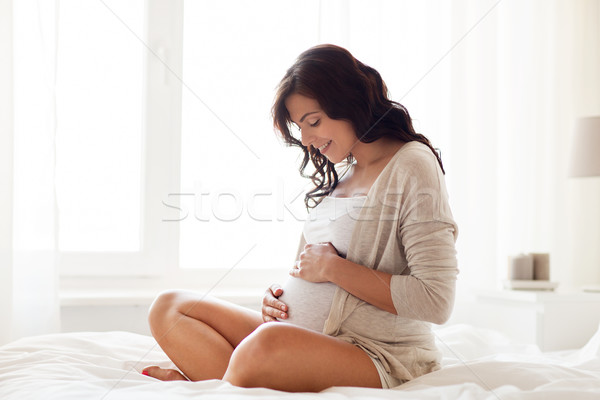 Heureux femme enceinte séance lit maison grossesse [[stock_photo]] © dolgachov