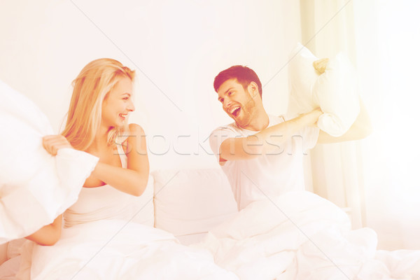 Heureux couple bataille d'oreillers lit maison personnes [[stock_photo]] © dolgachov