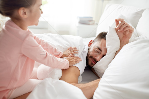 little girl waking her sleeping father up in bed Stock photo © dolgachov