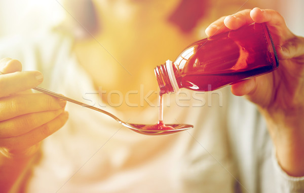 woman pouring medication from bottle to spoon Stock photo © dolgachov