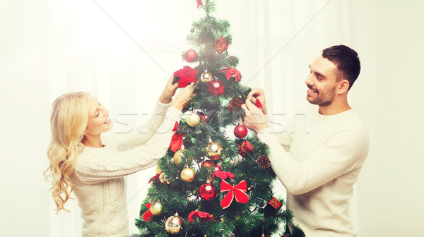 happy couple decorating christmas tree at home Stock photo © dolgachov